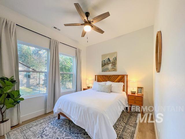 bedroom with visible vents, baseboards, wood finished floors, and a ceiling fan