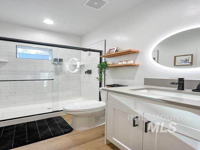 full bathroom featuring a stall shower, visible vents, toilet, and wood finished floors