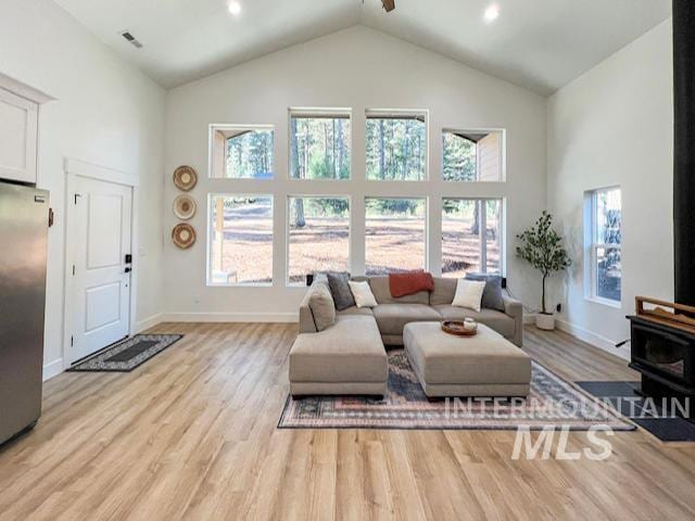 living room with plenty of natural light, high vaulted ceiling, and light wood-type flooring