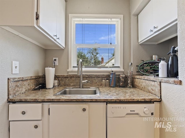 kitchen featuring dishwasher, white cabinets, a textured wall, and a sink