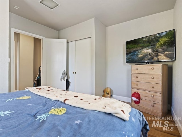 bedroom featuring a closet, baseboards, and wood finished floors