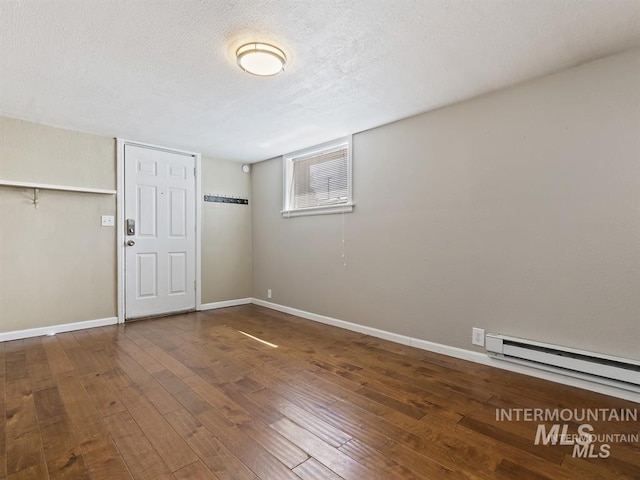 unfurnished room featuring a textured ceiling, a baseboard heating unit, baseboards, and hardwood / wood-style floors