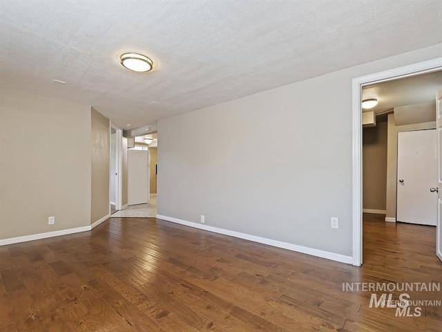 unfurnished room with hardwood / wood-style flooring, baseboards, and a textured ceiling
