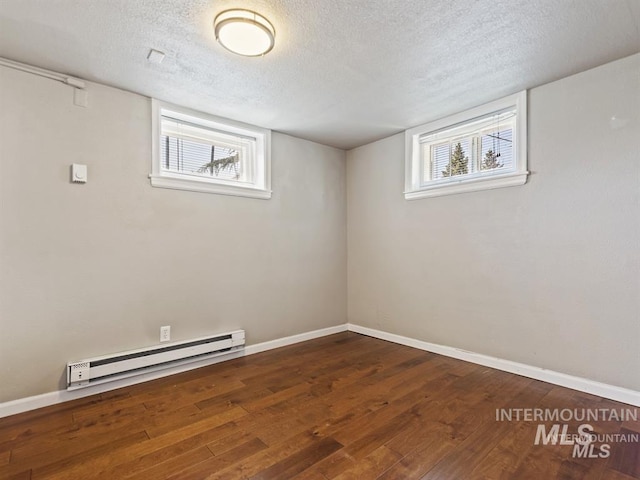 basement with a wealth of natural light, baseboard heating, baseboards, and hardwood / wood-style floors
