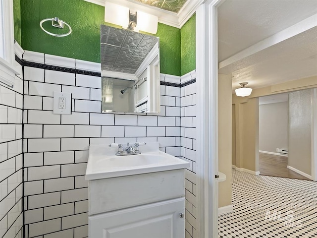 bathroom with vanity, baseboards, tiled shower, tile walls, and baseboard heating