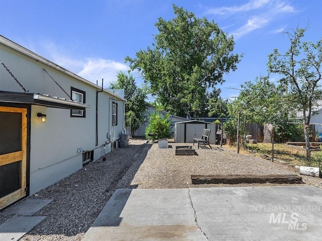 view of yard with an outbuilding, a shed, a patio area, and fence