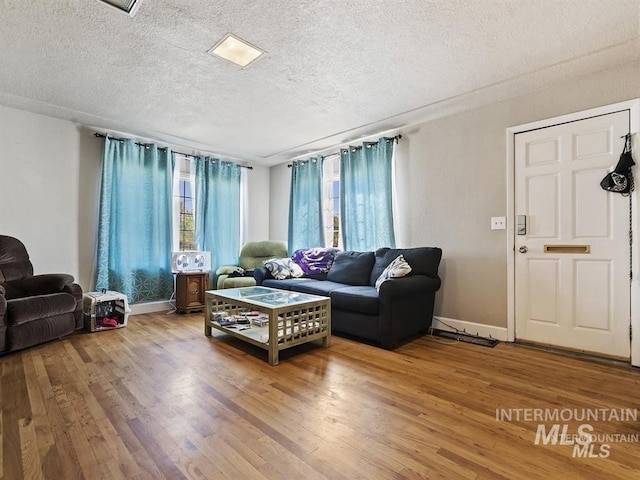 living room featuring baseboards, a textured ceiling, and wood finished floors