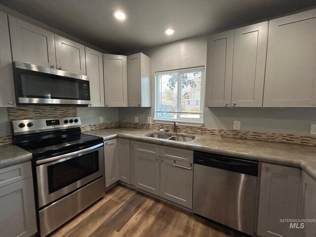 kitchen with sink, stainless steel appliances, dark wood-type flooring, and decorative backsplash