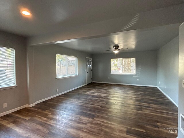 empty room featuring ceiling fan, dark wood-type flooring, and a healthy amount of sunlight