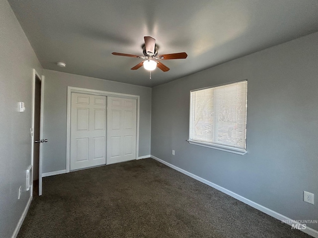 unfurnished bedroom featuring dark colored carpet, ceiling fan, and a closet