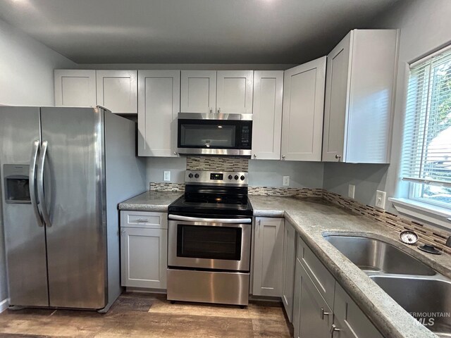 kitchen with sink, stainless steel appliances, white cabinetry, and light wood-type flooring