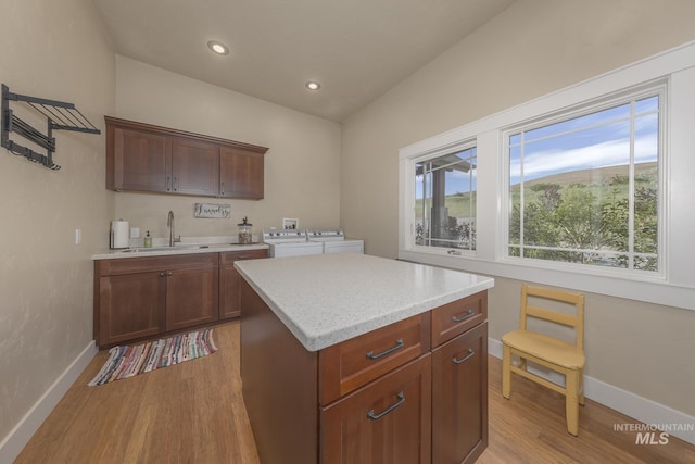 kitchen featuring a sink, washing machine and dryer, light wood-style floors, baseboards, and recessed lighting