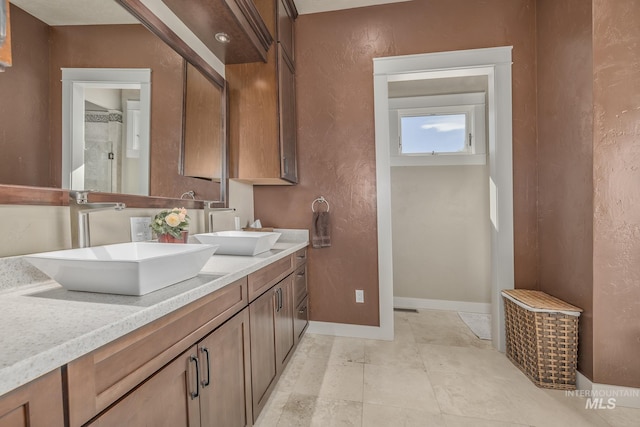 bathroom with double vanity, baseboards, and a textured wall