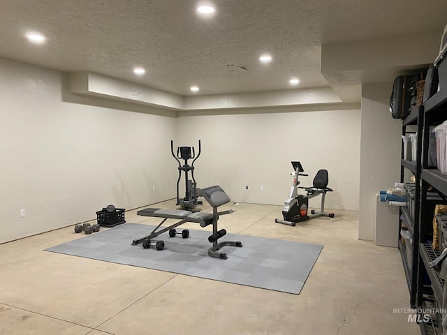 exercise area featuring recessed lighting, a tray ceiling, and a textured ceiling