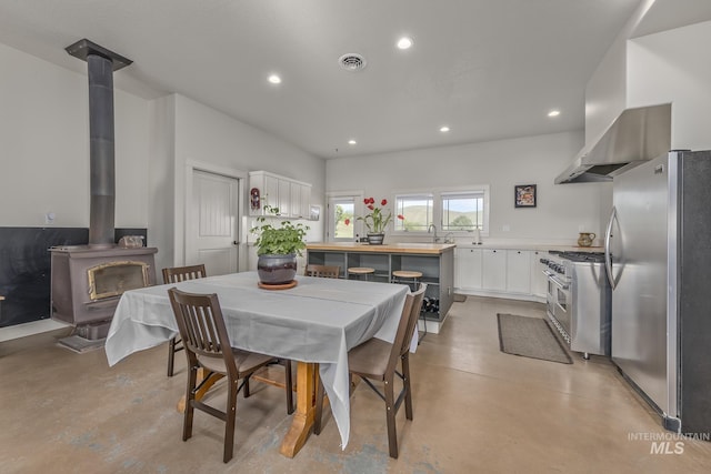 dining area featuring a wood stove, finished concrete floors, and recessed lighting