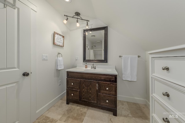 bathroom featuring baseboards, vaulted ceiling, and vanity