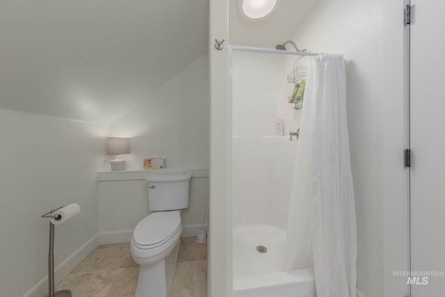 bathroom featuring a stall shower, toilet, lofted ceiling, and baseboards