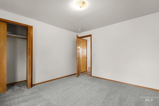 unfurnished bedroom with a closet, baseboards, and carpet flooring