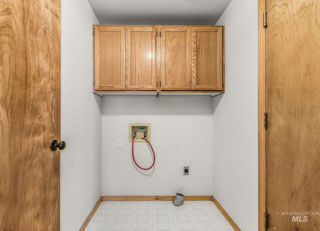 washroom featuring hookup for an electric dryer, cabinet space, baseboards, light floors, and hookup for a washing machine