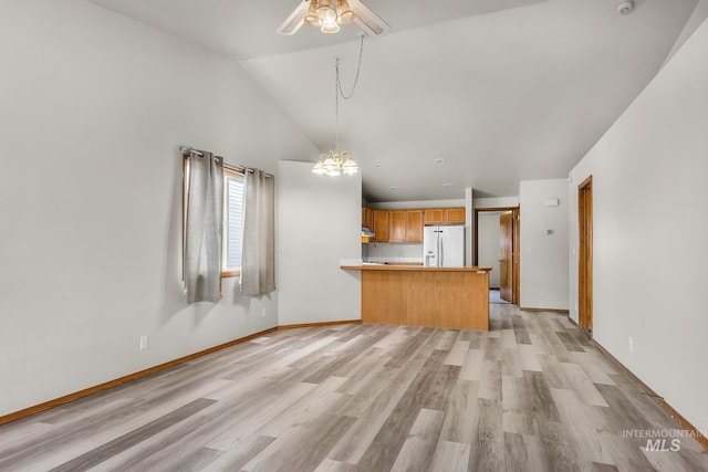 unfurnished living room featuring baseboards, high vaulted ceiling, light wood-style flooring, and ceiling fan with notable chandelier