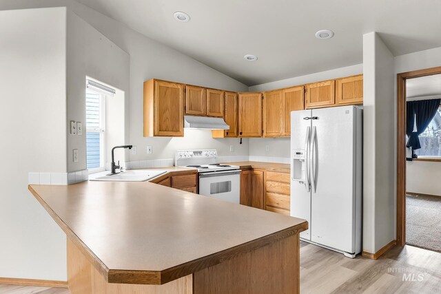 kitchen with white appliances, lofted ceiling, a peninsula, a sink, and under cabinet range hood