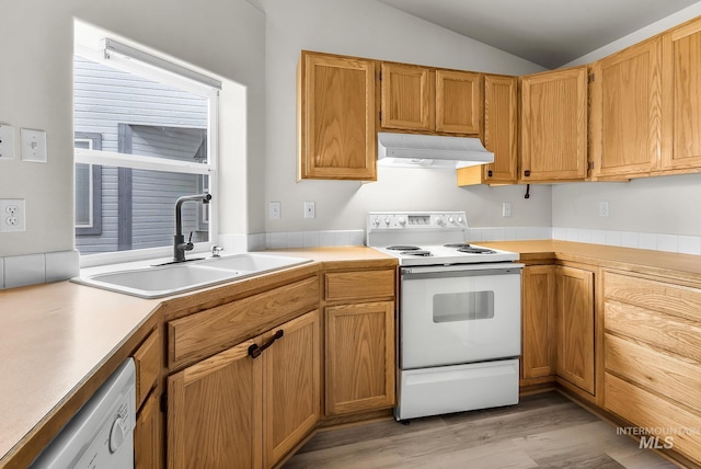 kitchen with under cabinet range hood, light countertops, vaulted ceiling, white appliances, and a sink