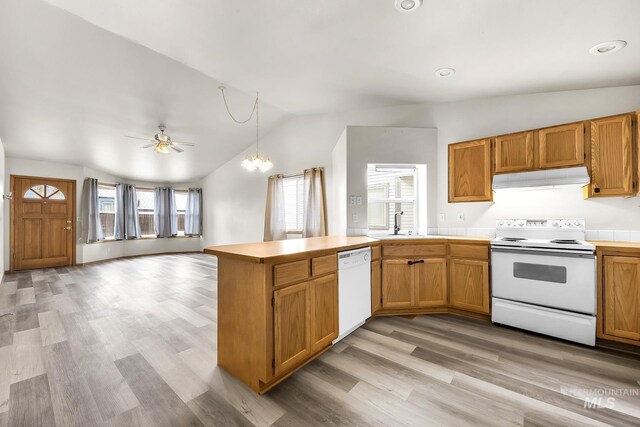 kitchen featuring under cabinet range hood, lofted ceiling, a peninsula, light wood-style floors, and white appliances