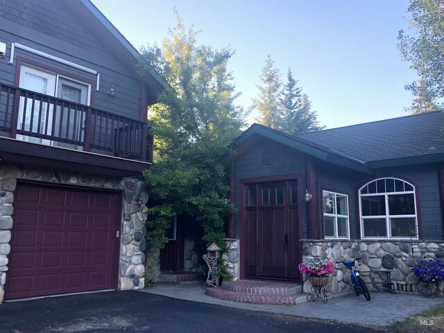 76 Rogers Ln, Mccall, ID 83638 - view of side of home featuring stone siding, a balcony, a shingled roof, and an attached garage
