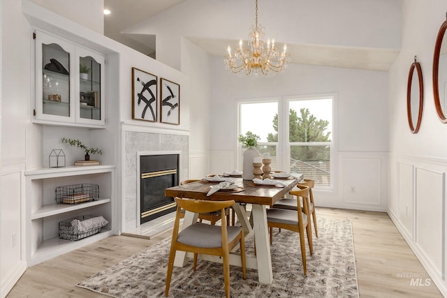 4335 W Quail Ridge Dr, Boise, ID 83703 - dining space featuring lofted ceiling, a chandelier, a tile fireplace, a wainscoted wall, and light wood-type flooring