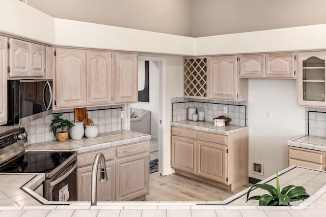 4335 W Quail Ridge Dr, Boise, ID 83703 - kitchen with stainless steel appliances, tile countertops, light brown cabinetry, and a towering ceiling