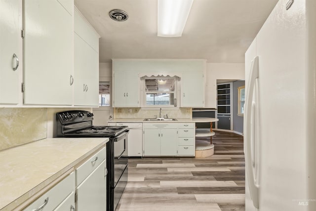 kitchen featuring sink, black electric range, white refrigerator, light hardwood / wood-style floors, and white cabinets