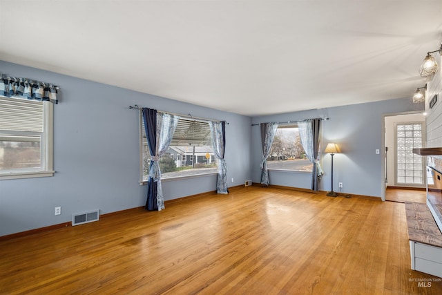 unfurnished living room featuring plenty of natural light and wood-type flooring