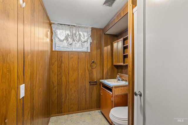 bathroom with wooden walls, vanity, and toilet