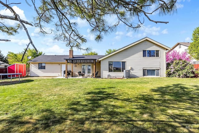 back of property featuring a pergola, a chimney, a patio area, a lawn, and a trampoline