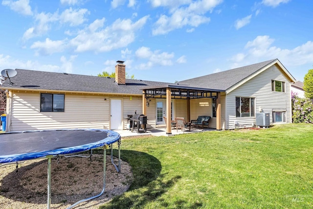back of property with a chimney, a trampoline, central air condition unit, a yard, and a patio