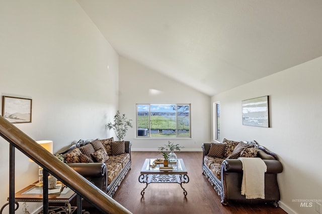 living area with baseboards, wood finished floors, and high vaulted ceiling