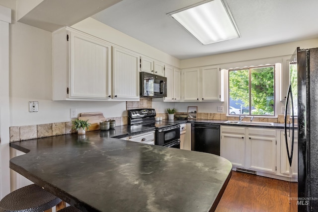 kitchen featuring visible vents, a peninsula, white cabinets, a sink, and black appliances