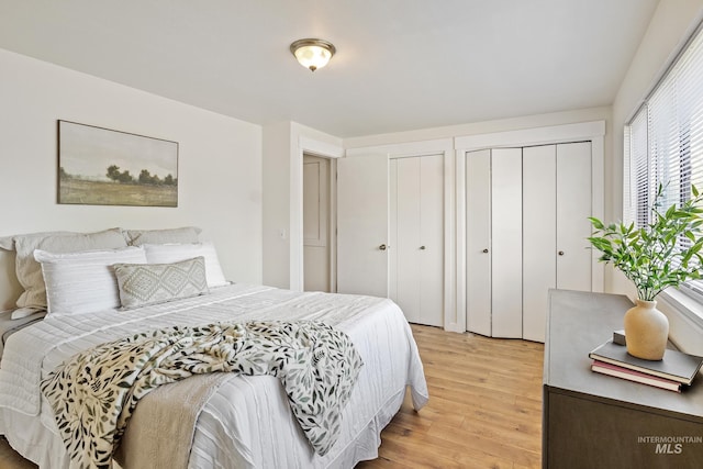 bedroom featuring two closets and light wood-style floors