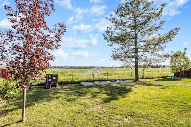 view of yard featuring fence, a vegetable garden, and a rural view