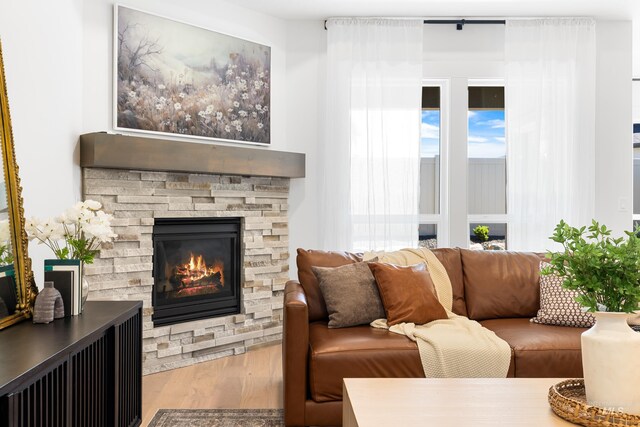 living area with wood finished floors and a stone fireplace
