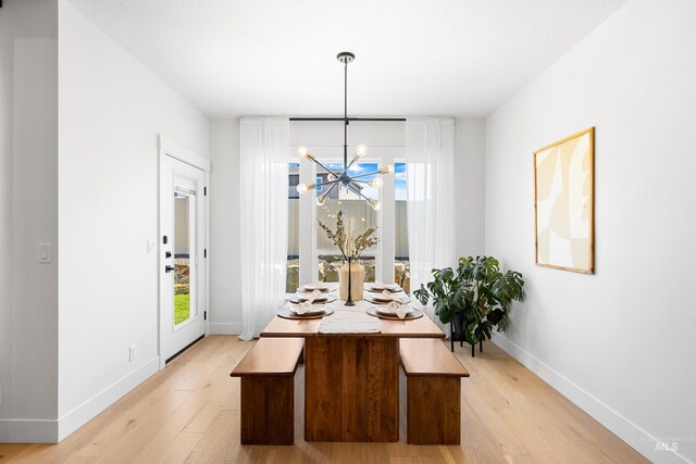 dining area with a chandelier, baseboards, and light wood-style flooring