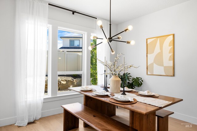 dining space featuring a chandelier, baseboards, and light wood finished floors