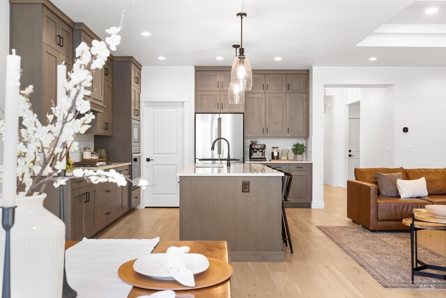 kitchen featuring stainless steel appliances, decorative backsplash, recessed lighting, light countertops, and a sink
