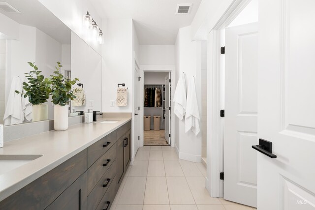 bathroom featuring tile patterned flooring, double vanity, a spacious closet, and baseboards