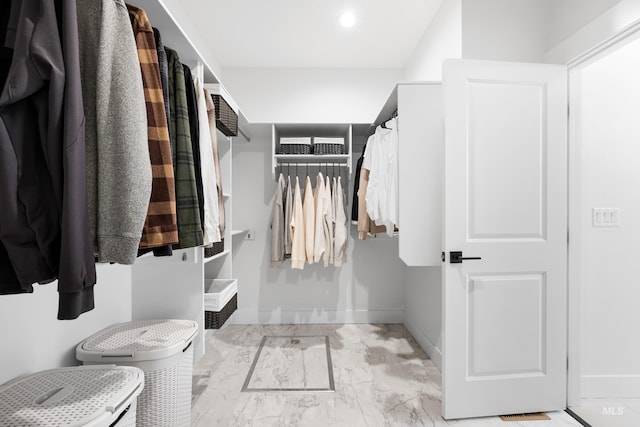 walk in closet with light marble finish flooring