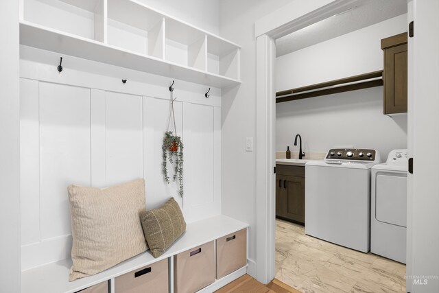 mudroom featuring independent washer and dryer, light marble finish flooring, and a sink