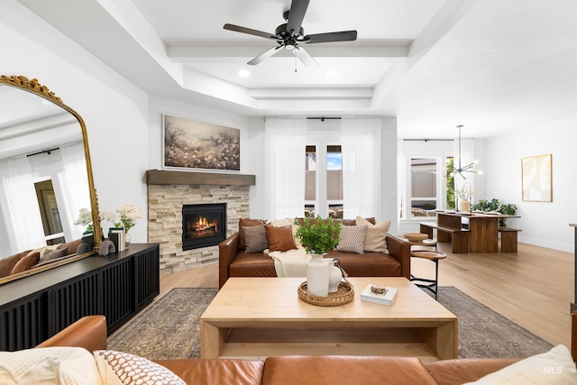living area with wood finished floors, a raised ceiling, ceiling fan, a fireplace, and recessed lighting