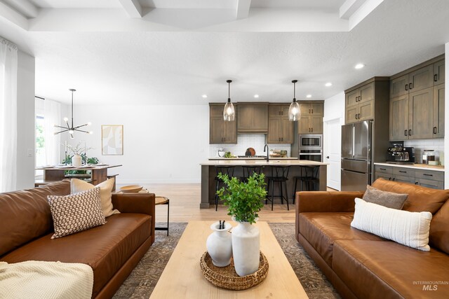 living area featuring recessed lighting, light wood finished floors, a chandelier, and baseboards