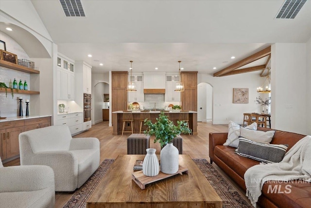 living area featuring light wood-type flooring, visible vents, arched walkways, and recessed lighting