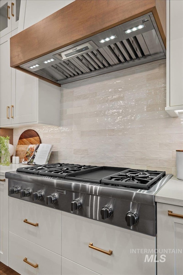 kitchen with stainless steel gas cooktop, white cabinetry, ventilation hood, and light countertops